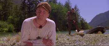 Movie still from “Alaska” (1996), directed by Fraser C. Heston – A man in a hat and a man with a camera in a field; Medium shot, Low angle