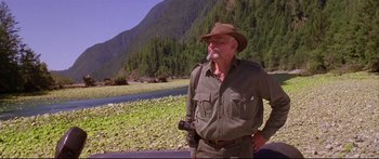 Movie still from “Alaska” (1996), directed by Fraser C. Heston – An older man with a beard and a hat is holding a camera; Medium shot, Low angle