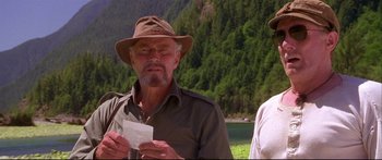 Movie still from “Alaska” (1996), directed by Fraser C. Heston – An older man wearing a hat while looking at a piece of paper; Medium shot, Low angle