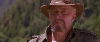 Movie still from “Alaska” (1996), directed by Fraser C. Heston – An older man wearing a brown hat and a brown jacket; Close Up shot, Over the shoulder angle