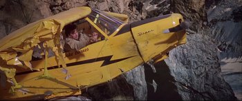 Movie still from “Alaska” (1996), directed by Fraser C. Heston – A yellow plane is sitting in the middle of a cliff; Wide shot, Overhead angle