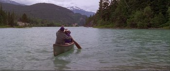 Movie still from “Alaska” (1996), directed by Fraser C. Heston – A group of people paddling a canoe on a lake; Extreme Wide shot, High angle