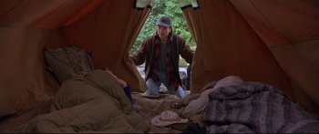 Movie still from “Alaska” (1996), directed by Fraser C. Heston – A person standing inside of a tent looking out the window; Medium shot, High angle