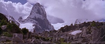 Movie still from “Alaska” (1996), directed by Fraser C. Heston – A person standing on top of a mountain near some rocks; Extreme Wide shot, High angle