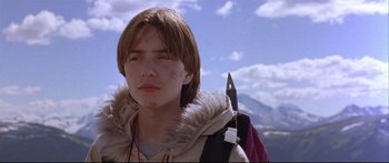 Movie still from “Alaska” (1996), directed by Fraser C. Heston – A man with a knife in his hand and a backpack; Close Up shot, Low angle