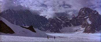 Movie still from “Alaska” (1996), directed by Fraser C. Heston – Two people are skiing on a snowy mountain; Extreme Wide shot, High angle