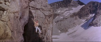 Movie still from “Alaska” (1996), directed by Fraser C. Heston – A man hanging from a rope on the side of a mountain; Wide shot, Low angle