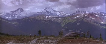 Movie still from “Alaska” (1996), directed by Fraser C. Heston – A helicopter sitting on top of a hill near some trees; Extreme Wide shot, High angle