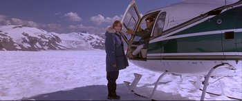 Movie still from “Alaska” (1996), directed by Fraser C. Heston – A woman standing in front of an open door of a helicopter; Wide shot, High angle