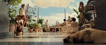 Movie still from “Alexander” (2004), directed by Oliver Stone – A group of people sitting at a table with a dog; Wide shot, Low angle