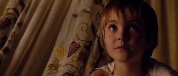 Movie still from “Alexander” (2004), directed by Oliver Stone – A little girl laying on a bed looking up at the camera; Close Up shot, High angle