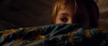 Movie still from “Alexander” (2004), directed by Oliver Stone – A young boy hiding under the covers of a bed; Close Up shot, Overhead angle