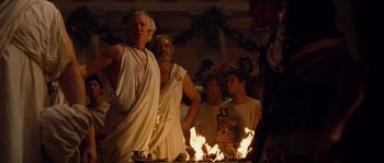 Movie still from “Alexander” (2004), directed by Oliver Stone – A group of people standing around a fire; Medium shot, Low angle