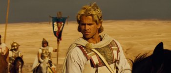 Movie still from “Alexander” (2004), directed by Oliver Stone – A person in a costume near a flag; Close Up shot, Over the shoulder angle