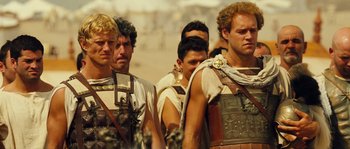 Movie still from “Alexander” (2004), directed by Oliver Stone – A group of men standing next to each other in roman garb; Medium shot, Over the shoulder angle