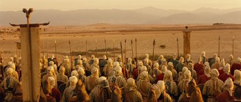 Movie still from “Alexander” (2004), directed by Oliver Stone – A large group of people are gathered together in the desert; Extreme Wide shot, High angle
