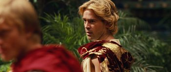 Movie still from “Alexander” (2004), directed by Oliver Stone – A man with blonde long hair wearing a red and gold outfit; Close Up shot, Over the shoulder angle