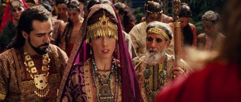 Movie still from “Alexander” (2004), directed by Oliver Stone – A couple of people that are dressed up; Medium shot, Over the shoulder angle