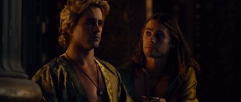 Movie still from “Alexander” (2004), directed by Oliver Stone – A man standing next to another man holding a drink; Close Up shot, Over the shoulder angle