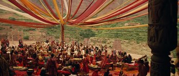 Movie still from “Alexander” (2004), directed by Oliver Stone – A group of people gathered under a colorful tent; Extreme Wide shot, High angle