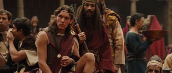 Movie still from “Alexander” (2004), directed by Oliver Stone – Two men dressed in ancient roman clothing and one is holding a spear; Medium shot, Over the shoulder angle