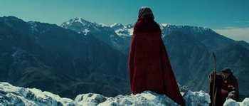 Movie still from “Alexander” (2004), directed by Oliver Stone – A person wearing a red blanket on top of a mountain; Extreme Wide shot, Low angle