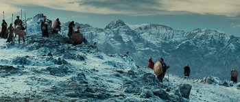 Movie still from “Alexander” (2004), directed by Oliver Stone – A group of people standing on top of a snow covered slope; Extreme Wide shot, Low angle