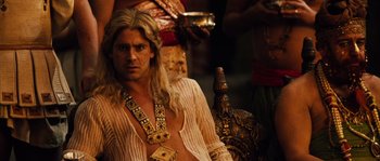 Movie still from “Alexander” (2004), directed by Oliver Stone – A man with long blonde hair sitting on a chair; Close Up shot, Over the shoulder angle