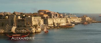 Movie still from “Alexander” (2004), directed by Oliver Stone – A view of a harbor with a boat in the water; Extreme Wide shot, High angle