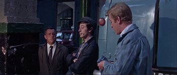 Movie still from “Alfie” (1966), directed by Lewis Gilbert – A group of men standing next to each other on the street; Medium shot, Over the shoulder angle