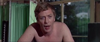 Movie still from “Alfie” (1966), directed by Lewis Gilbert – A man with a bare torso sitting in front of a window; Close Up shot, Over the shoulder angle