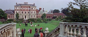 Movie still from “Alfie” (1966), directed by Lewis Gilbert – A group of people standing on a lush green field; Extreme Wide shot, High angle
