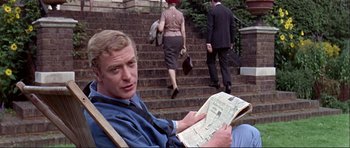 Movie still from “Alfie” (1966), directed by Lewis Gilbert – A man sitting on steps reading a newspaper; Medium shot, High angle