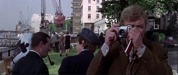 Movie still from “Alfie” (1966), directed by Lewis Gilbert – A man taking a picture of a crowd of onlookers; Medium shot, Over the shoulder angle