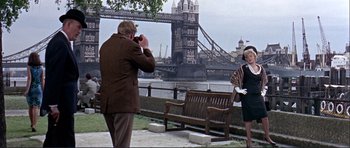 Movie still from “Alfie” (1966), directed by Lewis Gilbert – A man taking a picture of a woman in front of a bridge; Wide shot, Low angle
