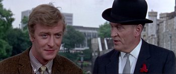 Movie still from “Alfie” (1966), directed by Lewis Gilbert – A man and a woman wearing suits and a hat; Close Up shot, Over the shoulder angle