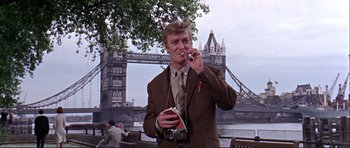 Movie still from “Alfie” (1966), directed by Lewis Gilbert – A man in a brown jacket and a camera; Medium shot, Low angle