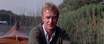Movie still from “Alfie” (1966), directed by Lewis Gilbert – A person wearing a sweater near a body of water; Close Up shot, Over the shoulder angle