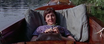 Movie still from “Alfie” (1966), directed by Lewis Gilbert – A woman sitting in a boat holding a plant; Medium shot, High angle
