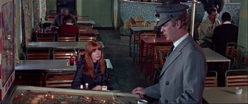 Movie still from “Alfie” (1966), directed by Lewis Gilbert – A woman sitting at a table in front of a man in a hat; Medium shot, High angle