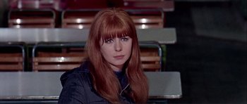Movie still from “Alfie” (1966), directed by Lewis Gilbert – A woman with long red hair sitting in front of a row of chairs; Close Up shot, Over the shoulder angle