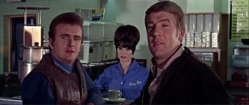 Movie still from “Alfie” (1966), directed by Lewis Gilbert – A group of people sitting at a table with a cup of coffee; Medium shot, Low angle