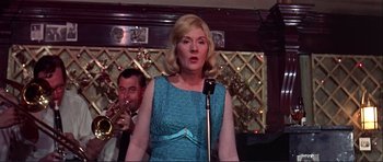 Movie still from “Alfie” (1966), directed by Lewis Gilbert – A woman in a blue dress singing into a microphone; Medium shot, Low angle