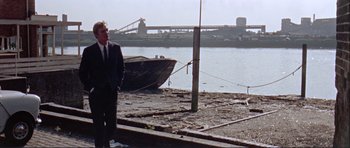 Movie still from “Alfie” (1966), directed by Lewis Gilbert – A man standing next to a body of water; Wide shot, Low angle