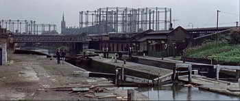 Movie still from “Alfie” (1966), directed by Lewis Gilbert – An old dock with some buildings in the background; Extreme Wide shot, High angle