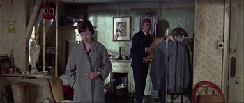 Movie still from “Alfie” (1966), directed by Lewis Gilbert – A man and a woman standing in front of a fireplace; Medium shot, High angle