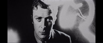 Movie still from “Alfie” (1966), directed by Lewis Gilbert – A black and white photo of a man in a suit and tie; Close Up shot, Low angle