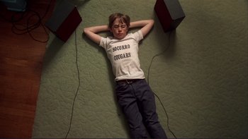 Movie still from “Alice Doesn't Live Here Anymore” (1974), directed by Martin Scorsese – A boy laying on the ground with his hands behind his head; Medium shot, Overhead angle