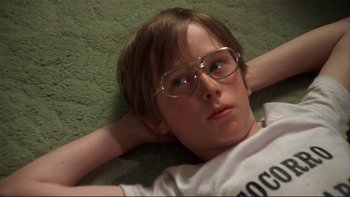 Movie still from “Alice Doesn't Live Here Anymore” (1974), directed by Martin Scorsese – A boy with glasses laying on the ground; Close Up shot, High angle