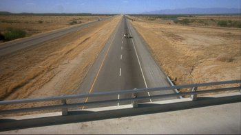 Movie still from “Alice Doesn't Live Here Anymore” (1974), directed by Martin Scorsese – An empty highway with a car driving down the road; Extreme Wide shot, High angle